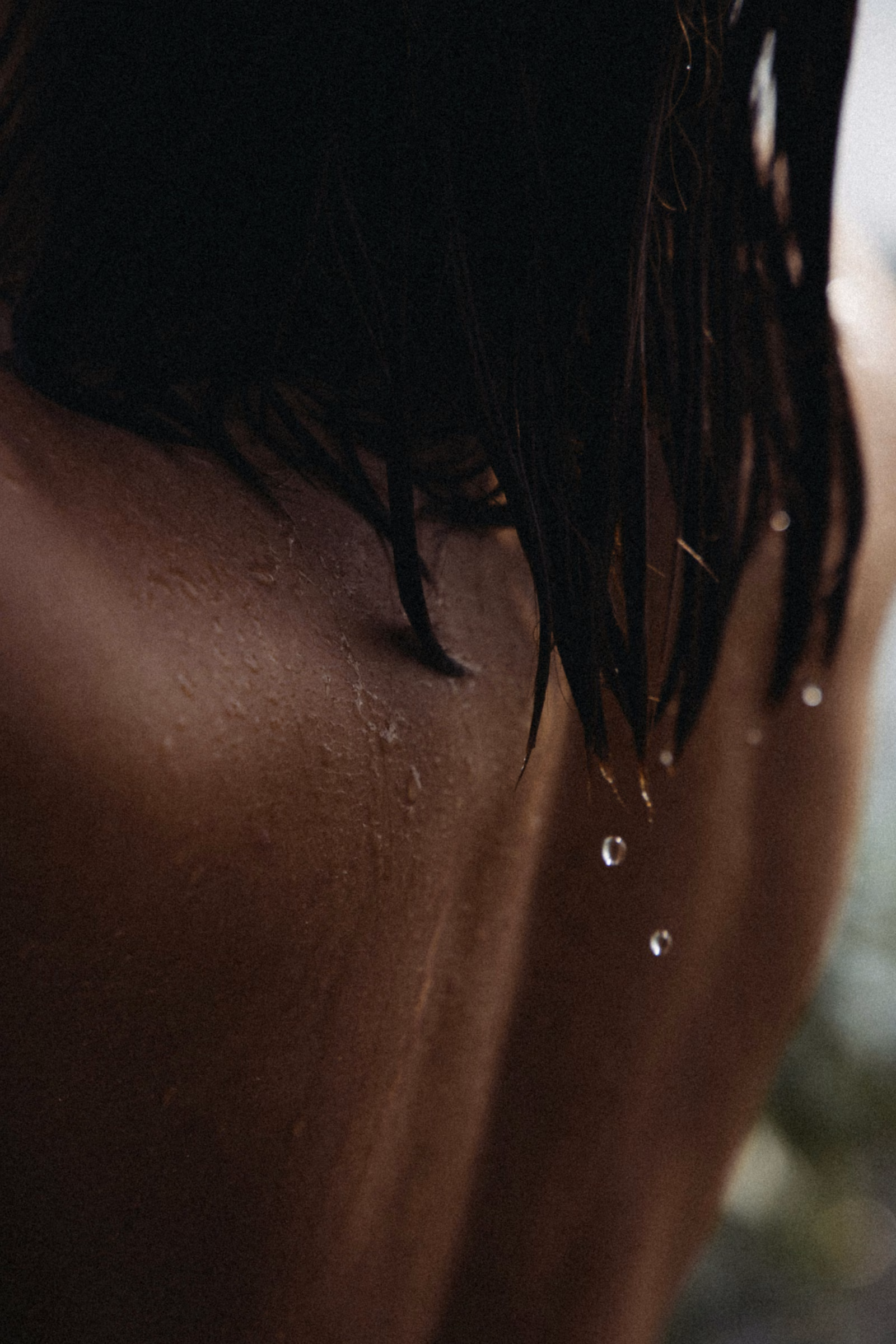 Water droplets falling from a woman’s wet hair over her shoulder